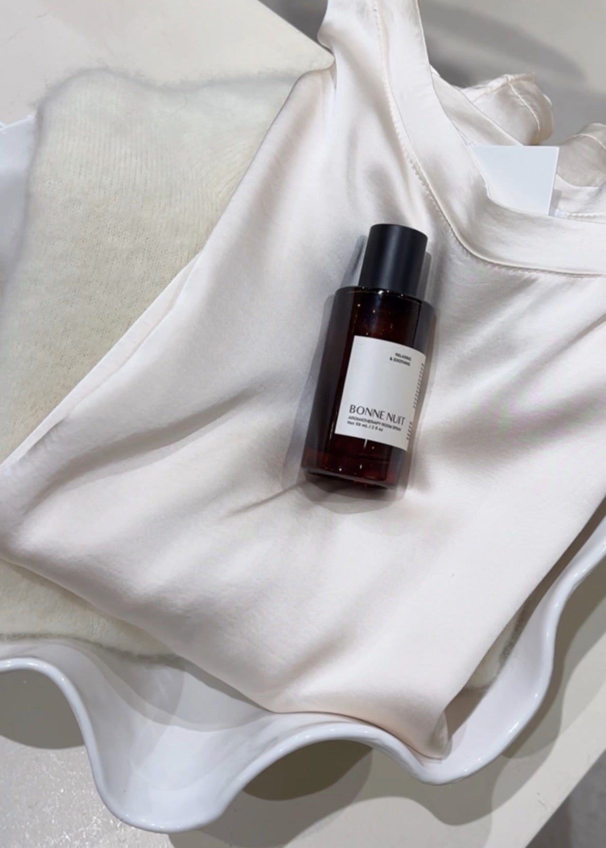 Small bottle of perfume on a white fabric background