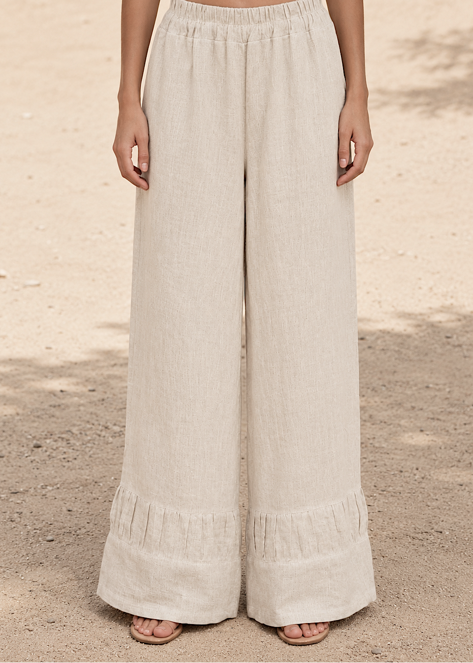 Beige wide-leg pants worn by a person on a neutral background