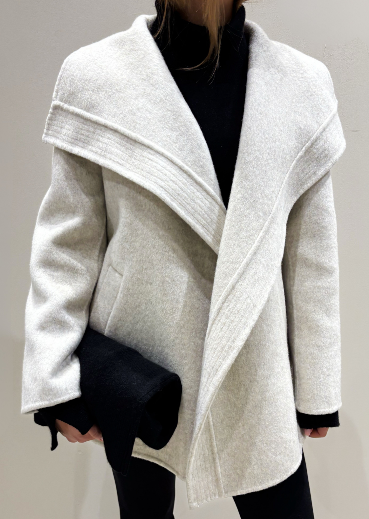 Person wearing a white coat with a black interior on a plain background