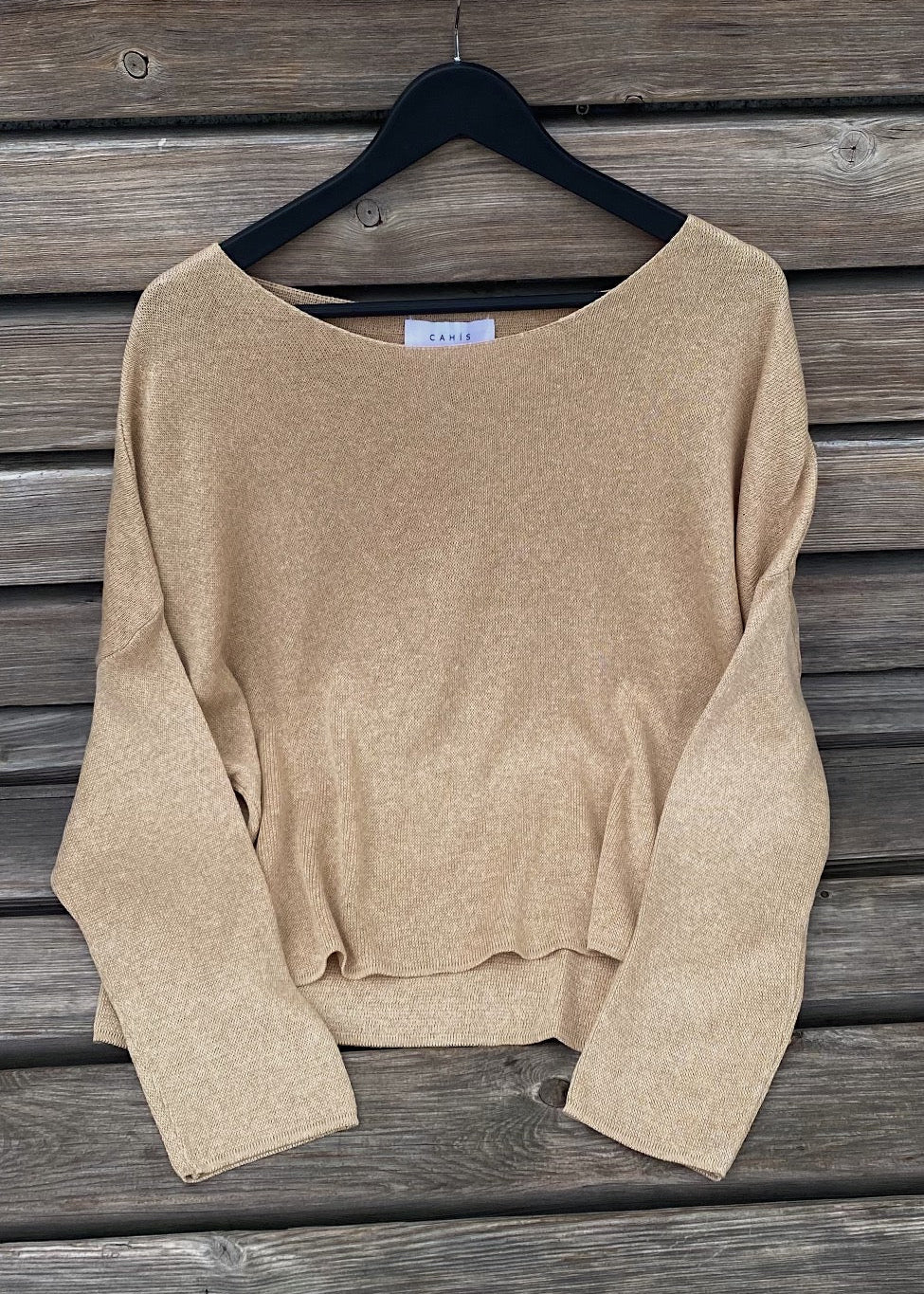 Beige sweater on a hanger against a wooden background