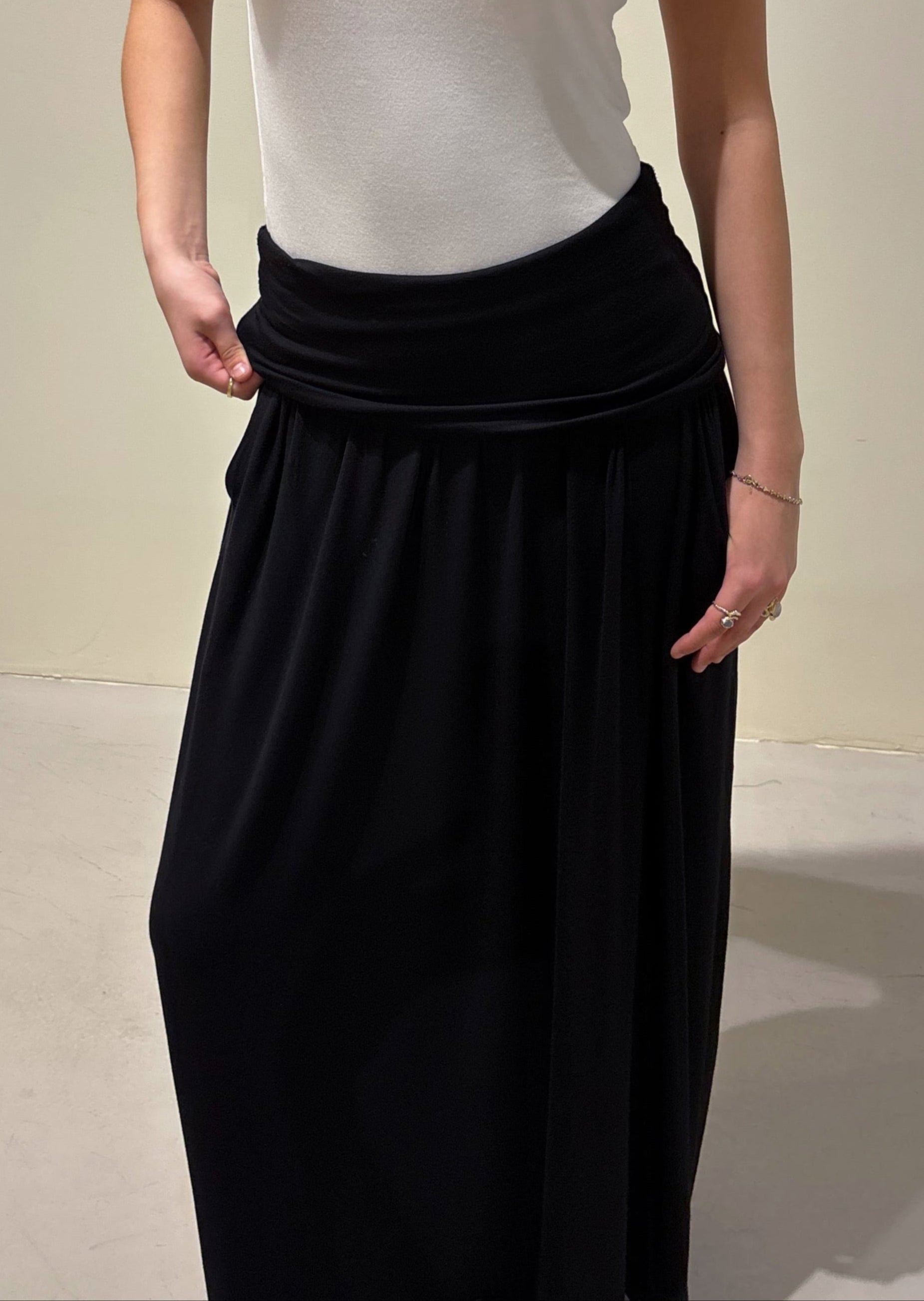Person wearing a white t-shirt and black skirt against a plain background