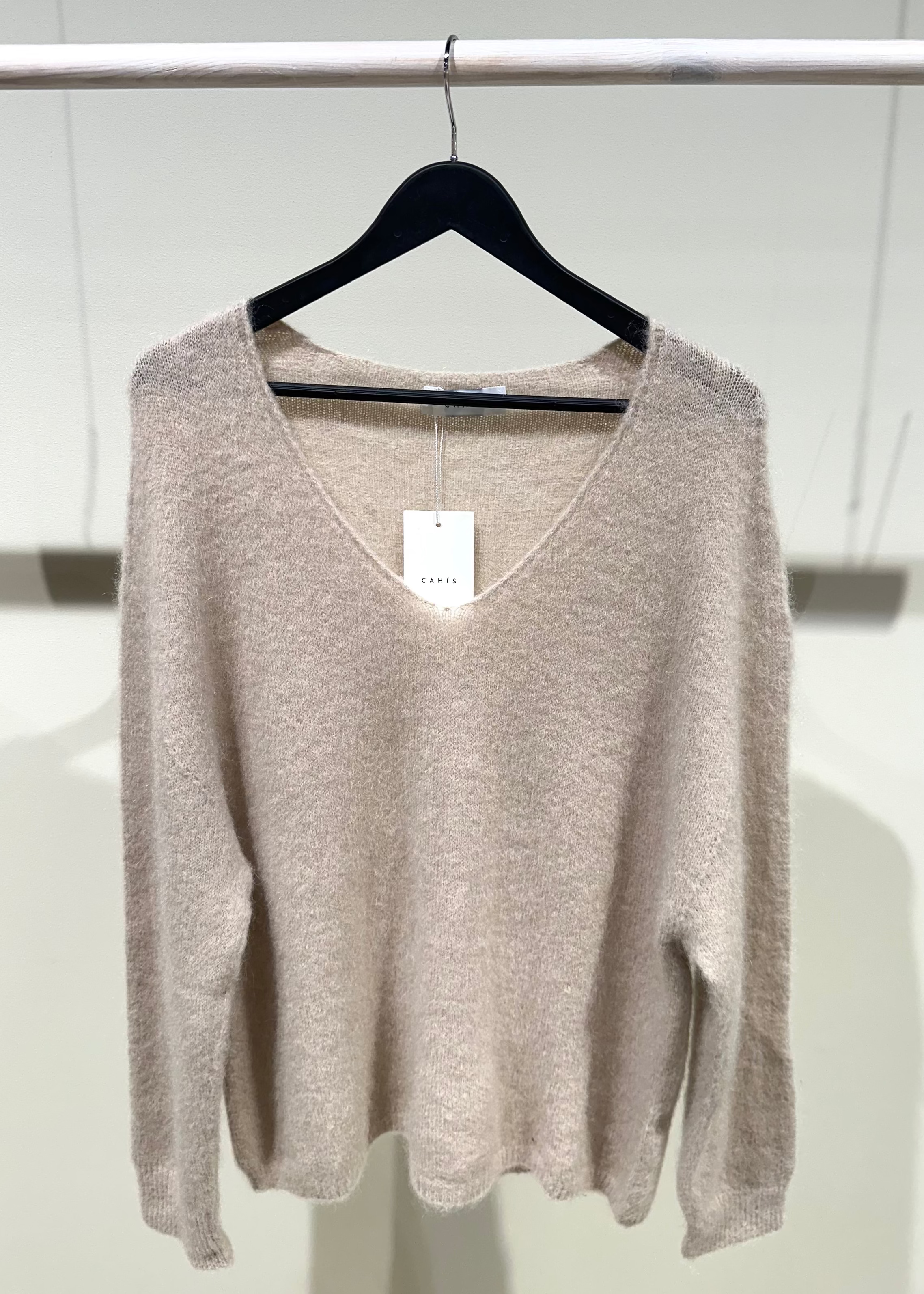 Beige sweater on a hanger against a white background