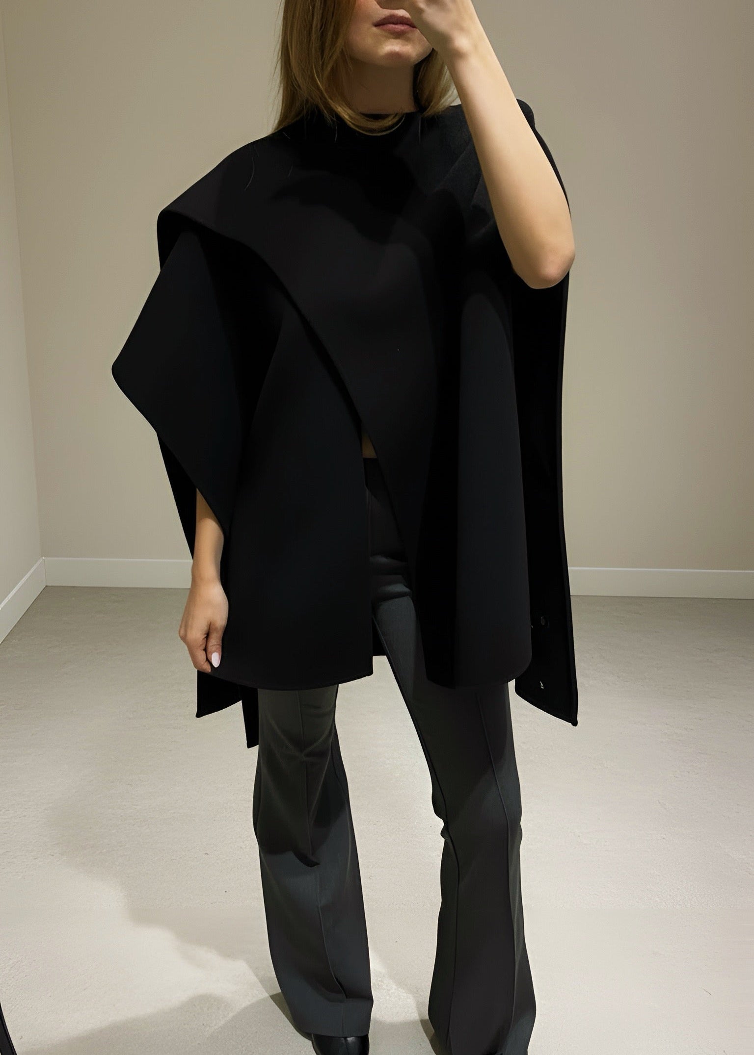 Person wearing a black outfit taking a mirror selfie.