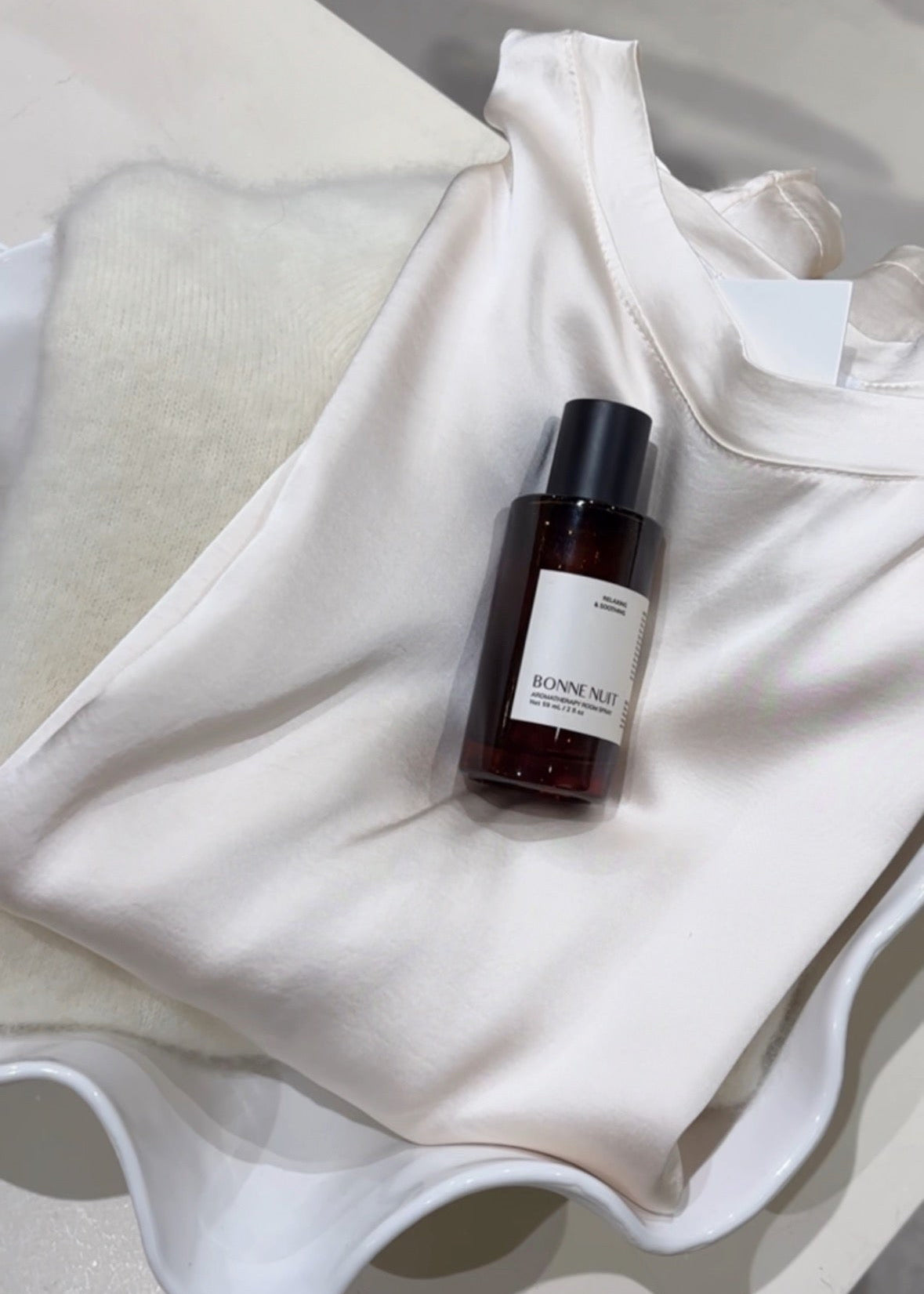 Small bottle of perfume on a white fabric background