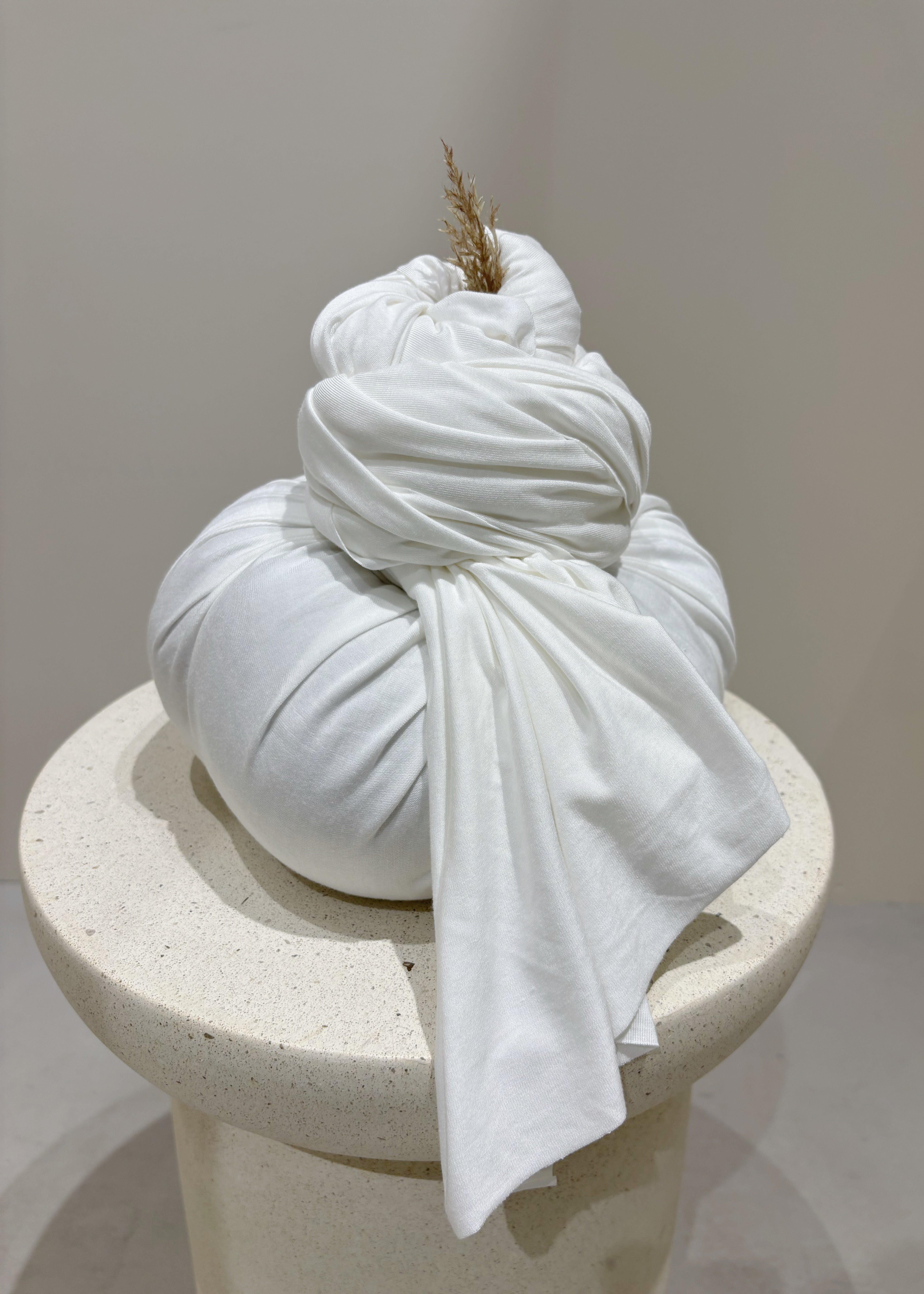 White fabric wrapped around a cylindrical object on a neutral background