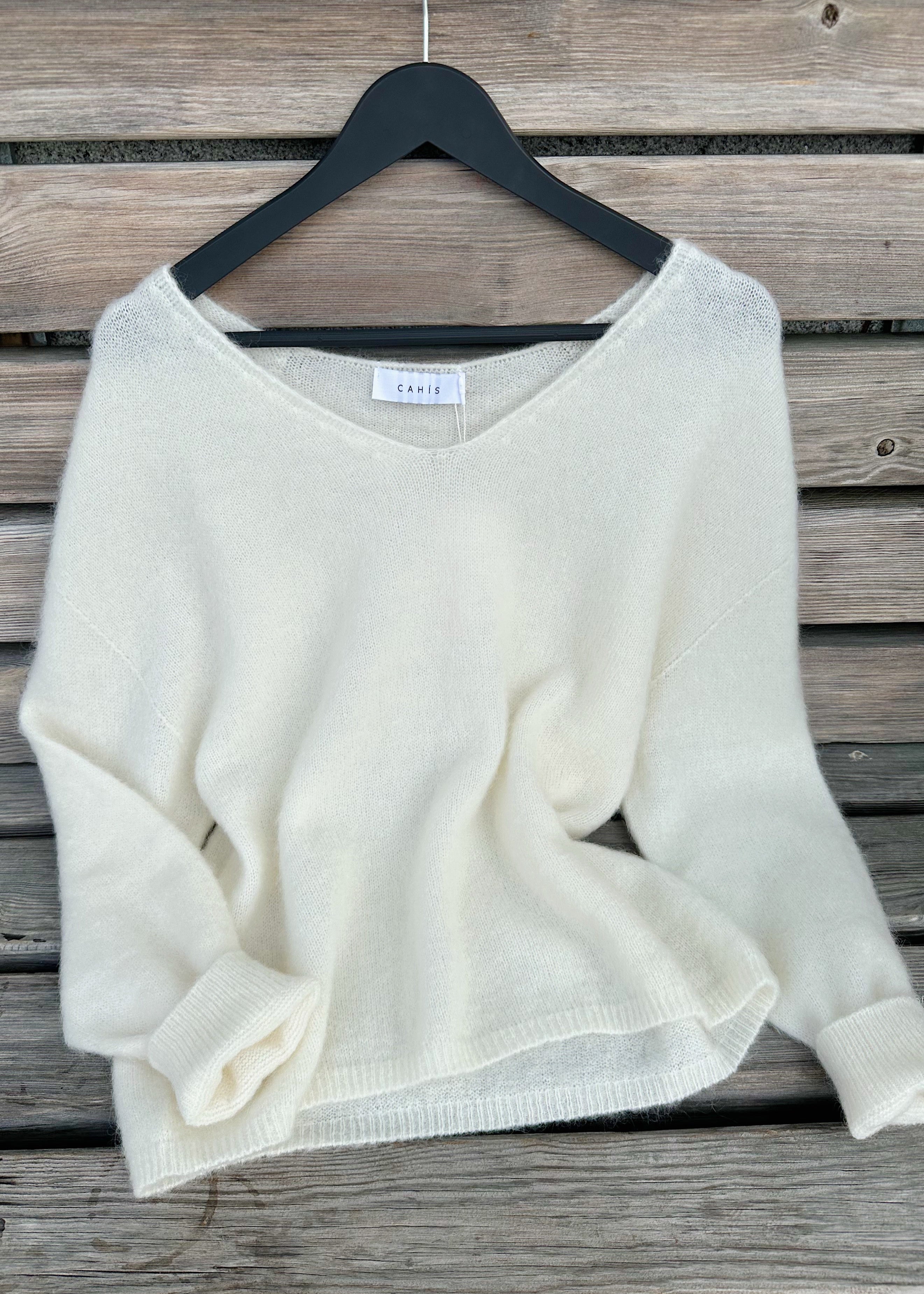 White sweater on a hanger against a wooden background