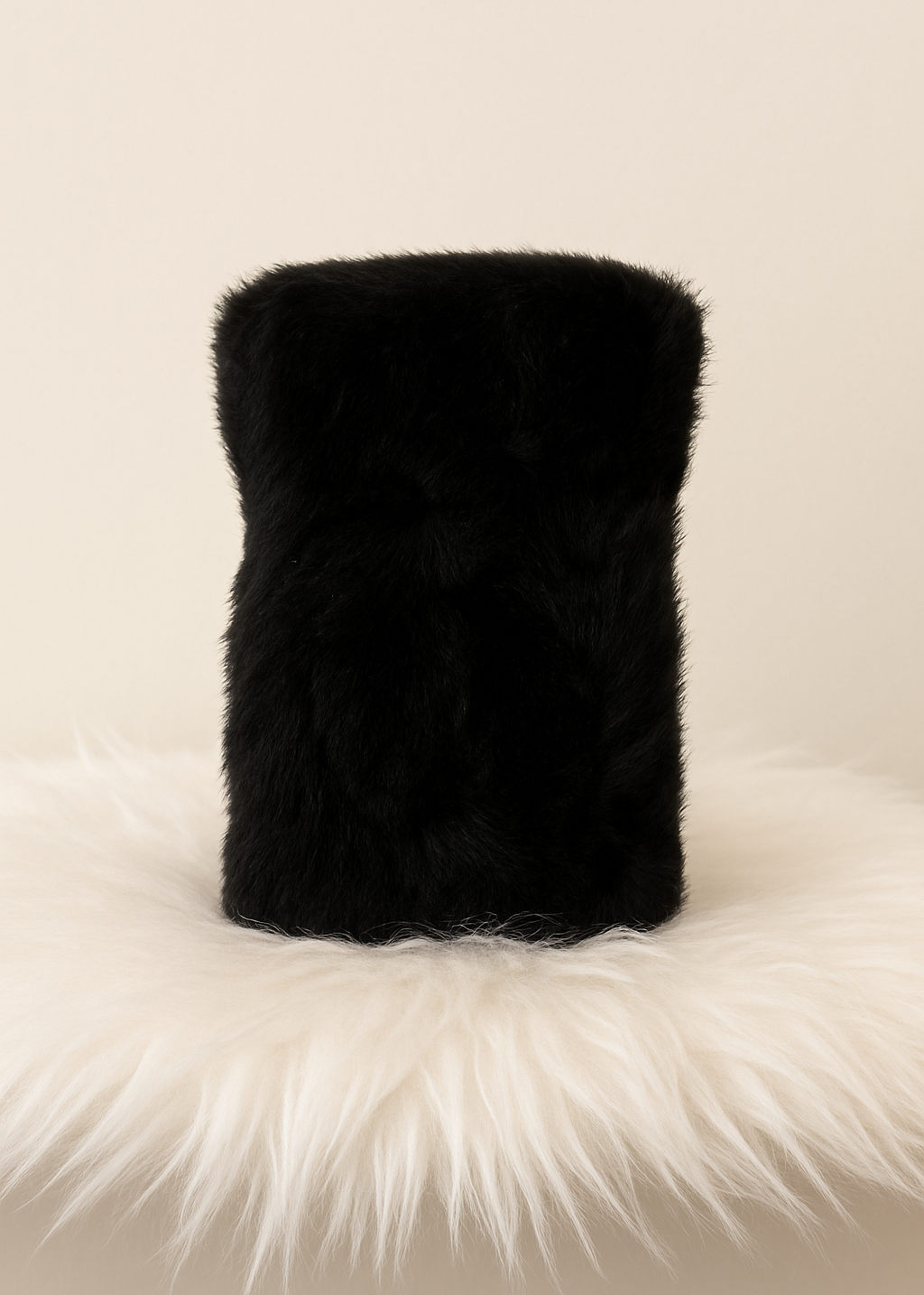Black fur pillow on a white fur surface