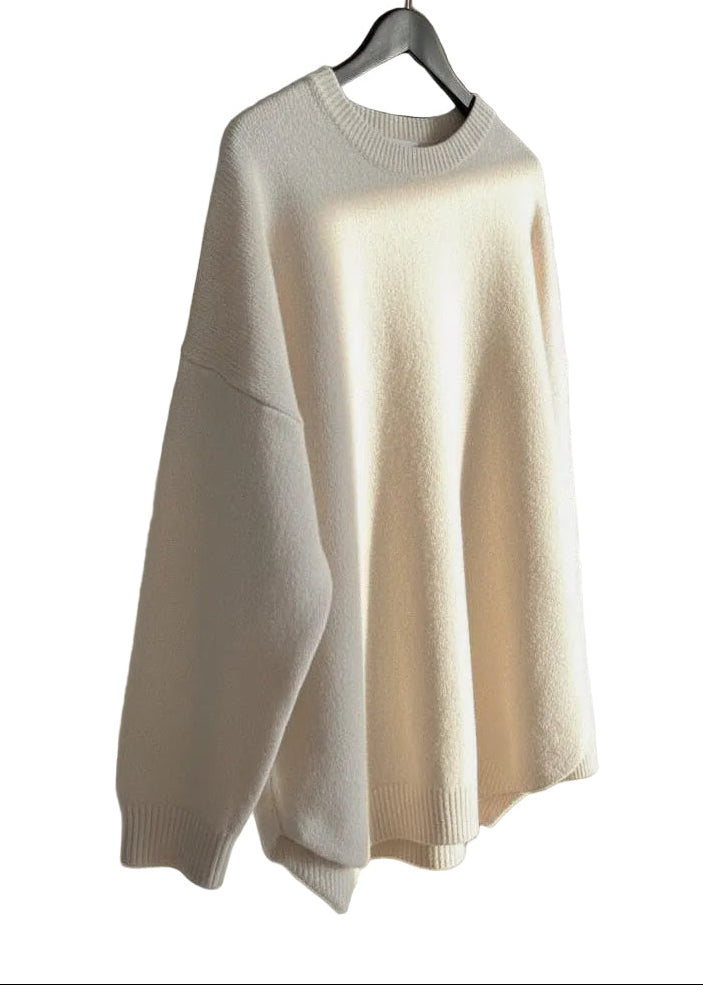 Beige sweater hanging on a hook in a well-lit room with shelves.