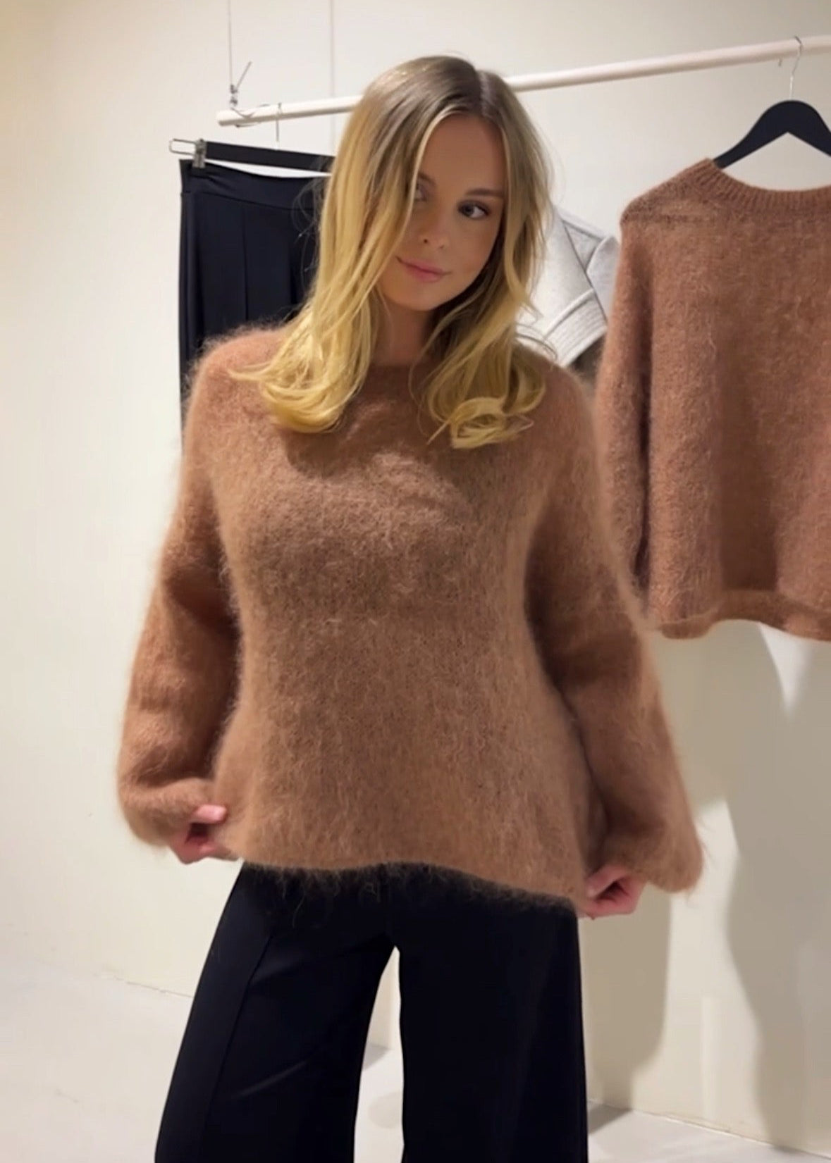 Woman wearing a brown sweater with a blurred background
