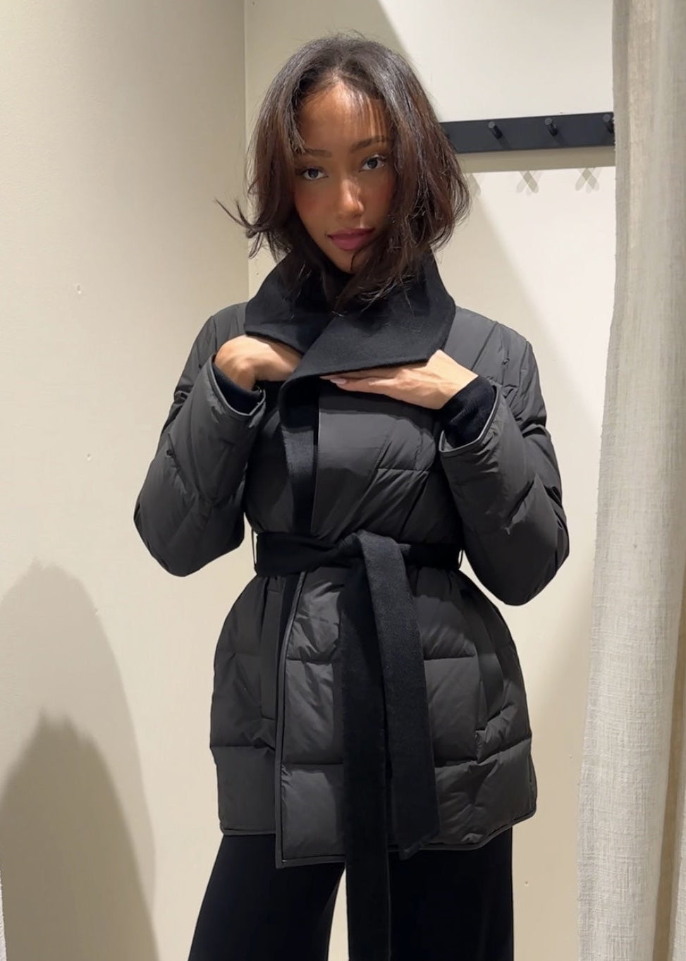 Person wearing a black puffer coat in a mirror selfie setting.