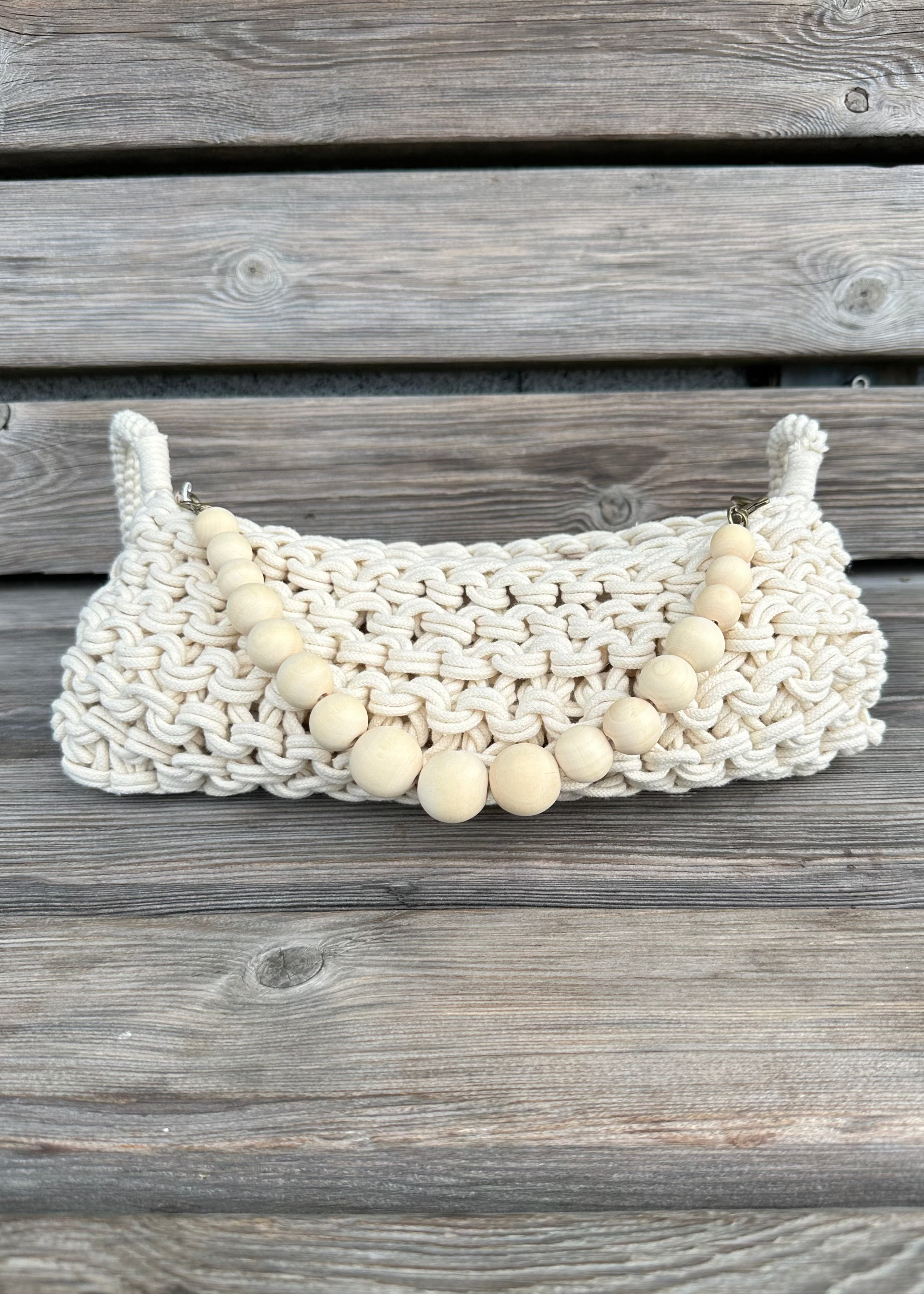 Woven macrame bag with wooden beads on a wooden surface