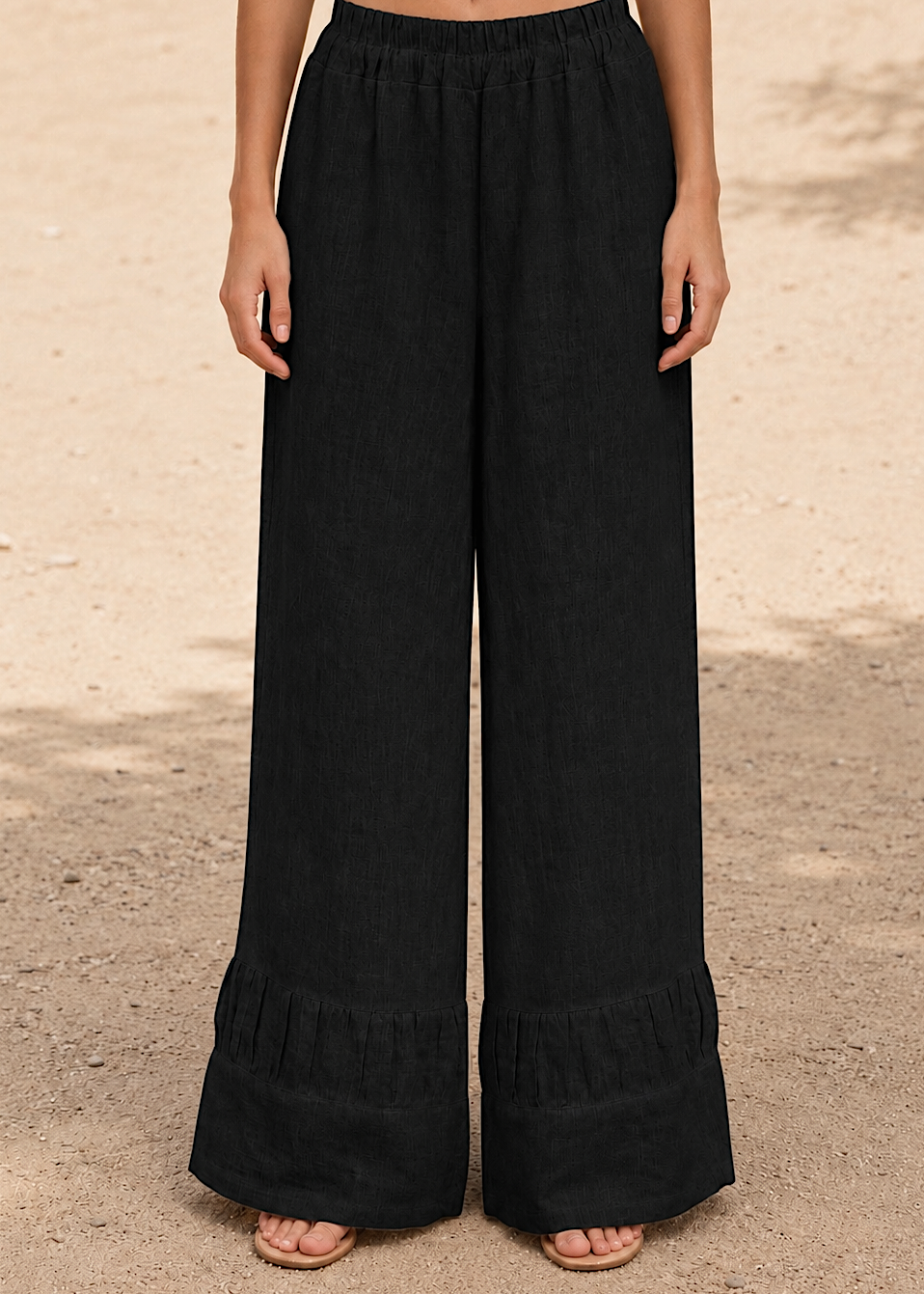Person wearing black wide-leg pants on a beige background