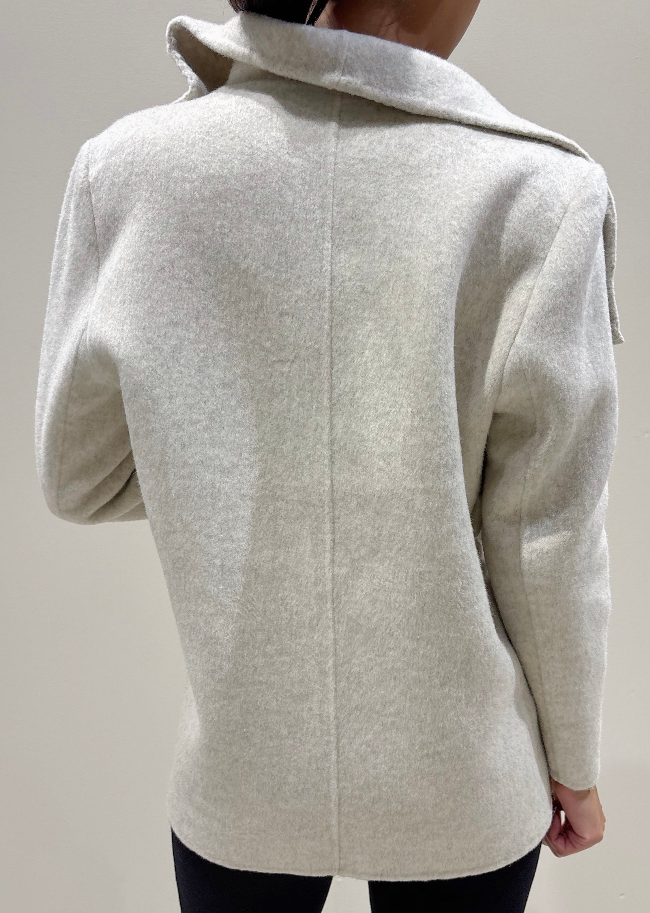 Light gray coat worn by a person on a plain background