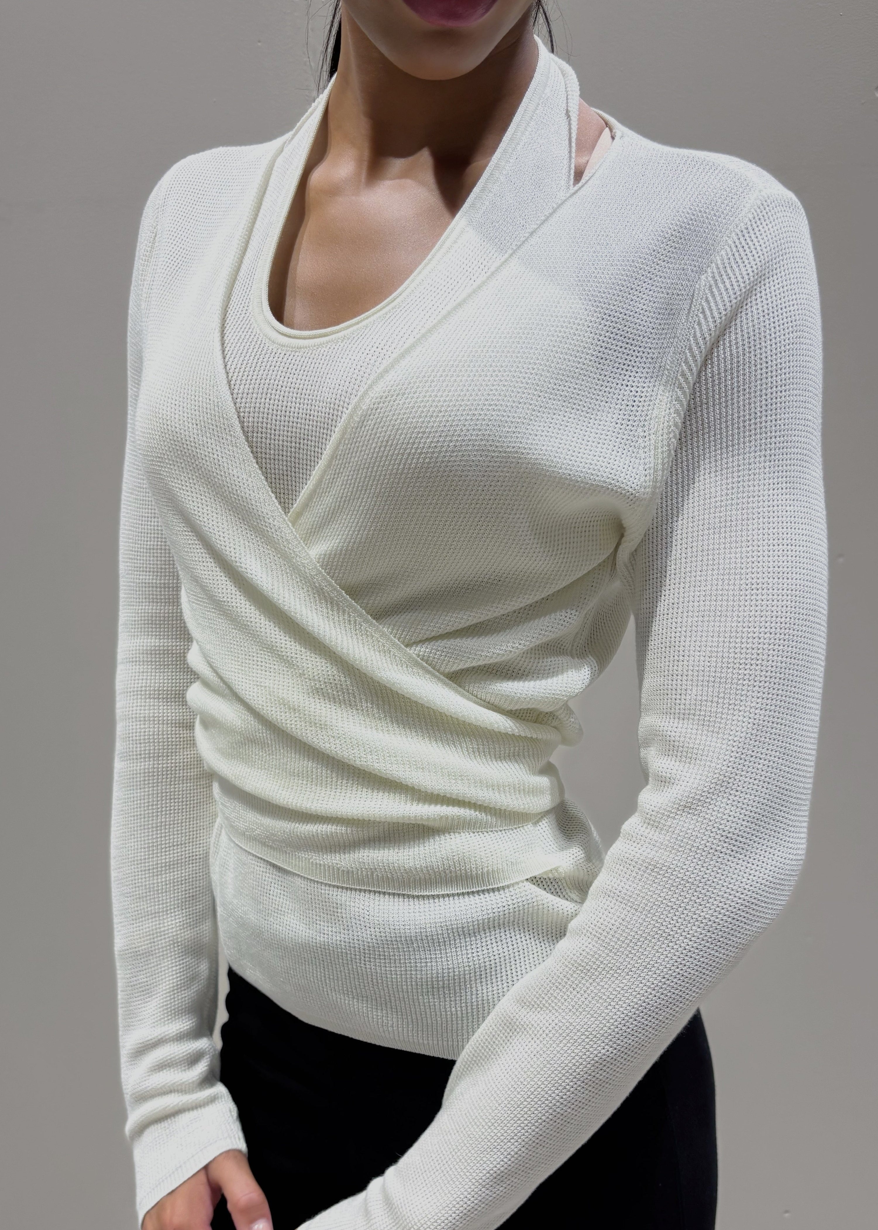 Person wearing a white long-sleeve top with a V-neckline against a neutral background