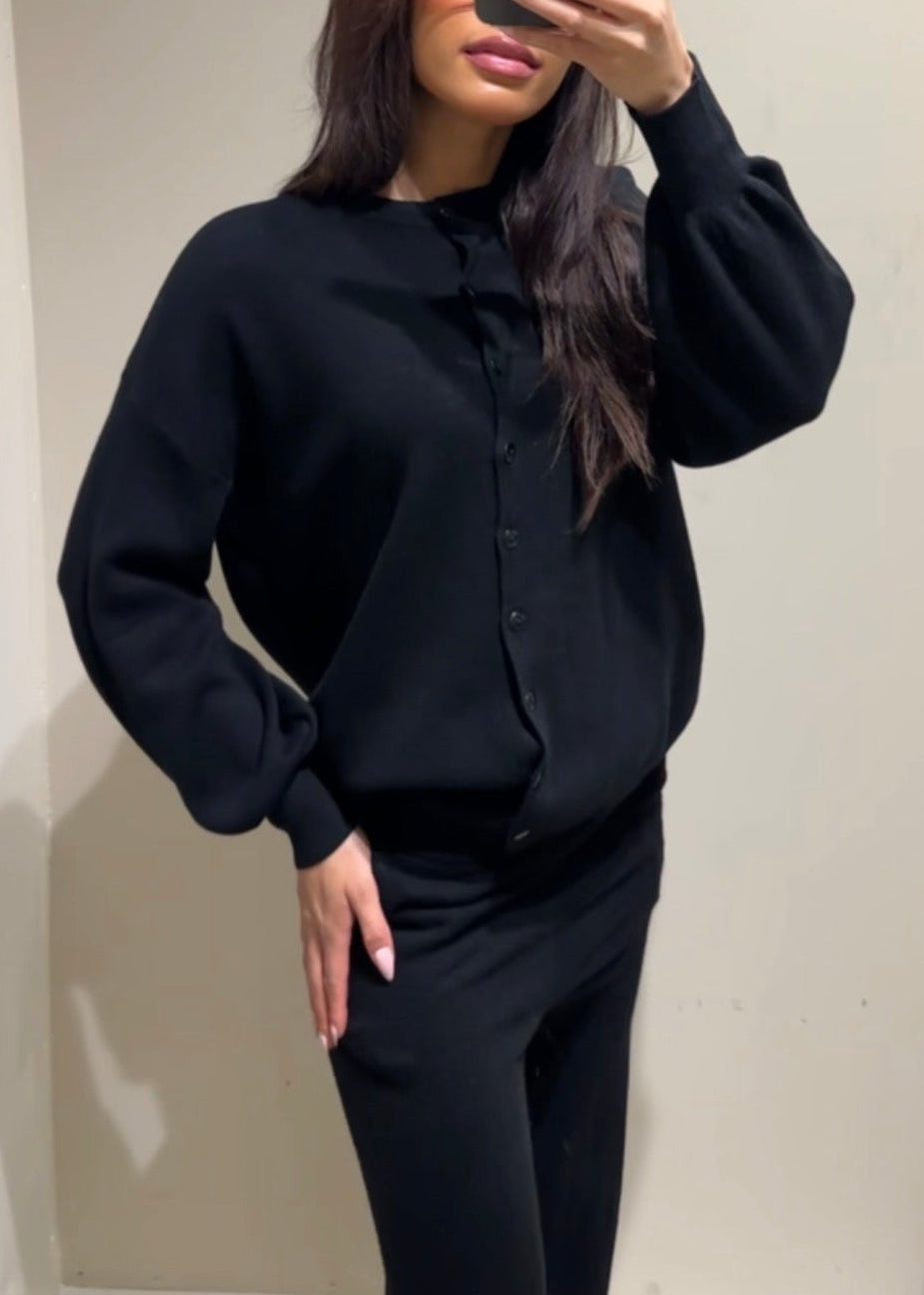 Person wearing a black outfit taking a mirror selfie.