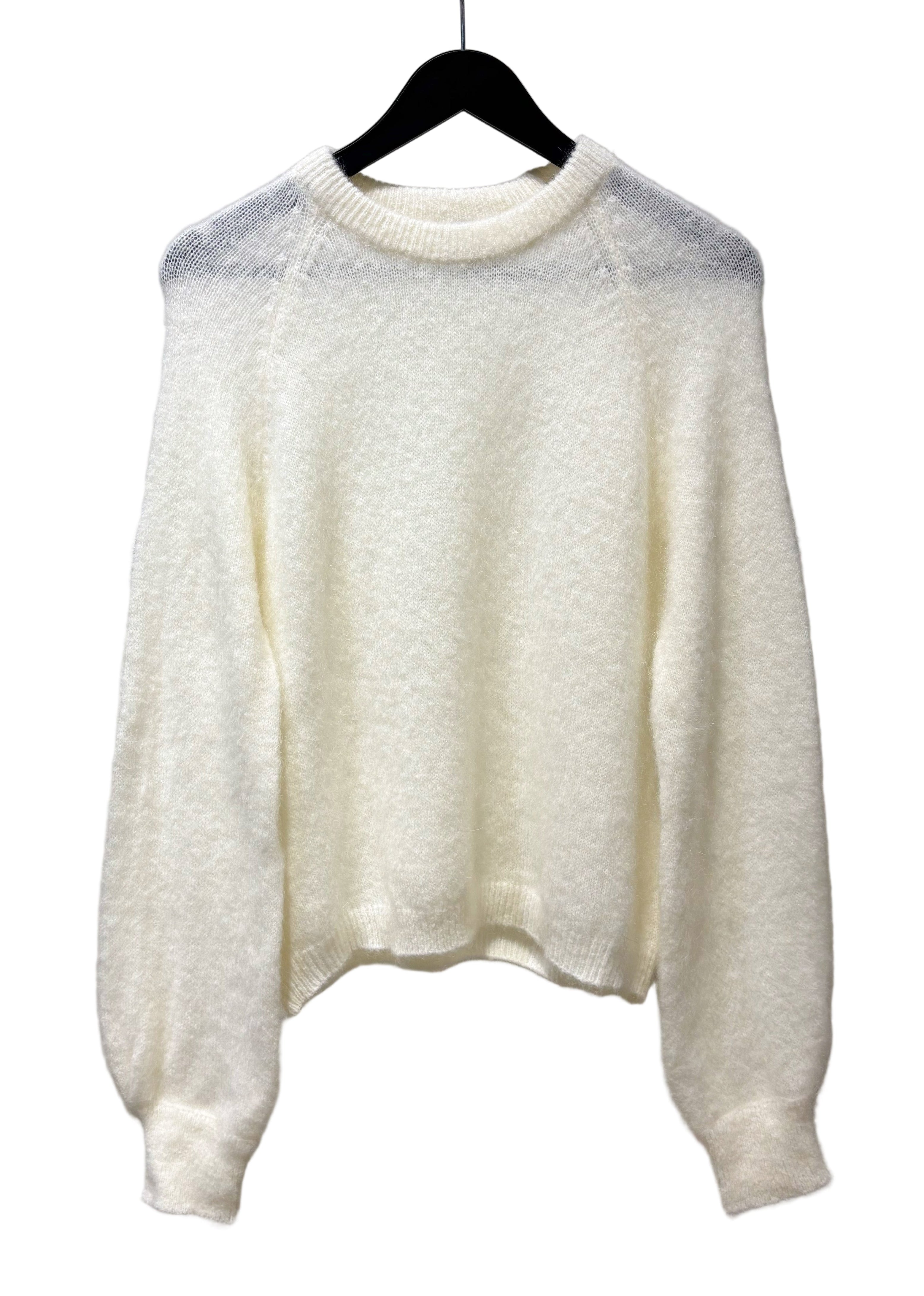 White textured sweater on a hanger against a plain background