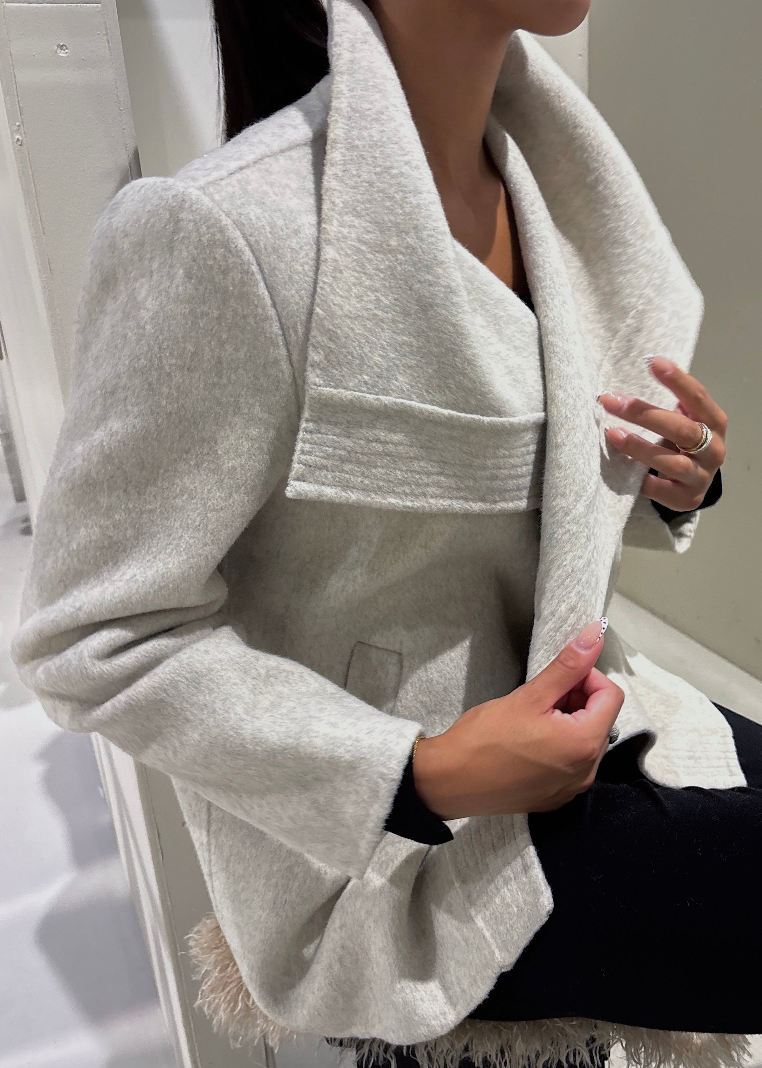 Person wearing a light gray coat with a white background