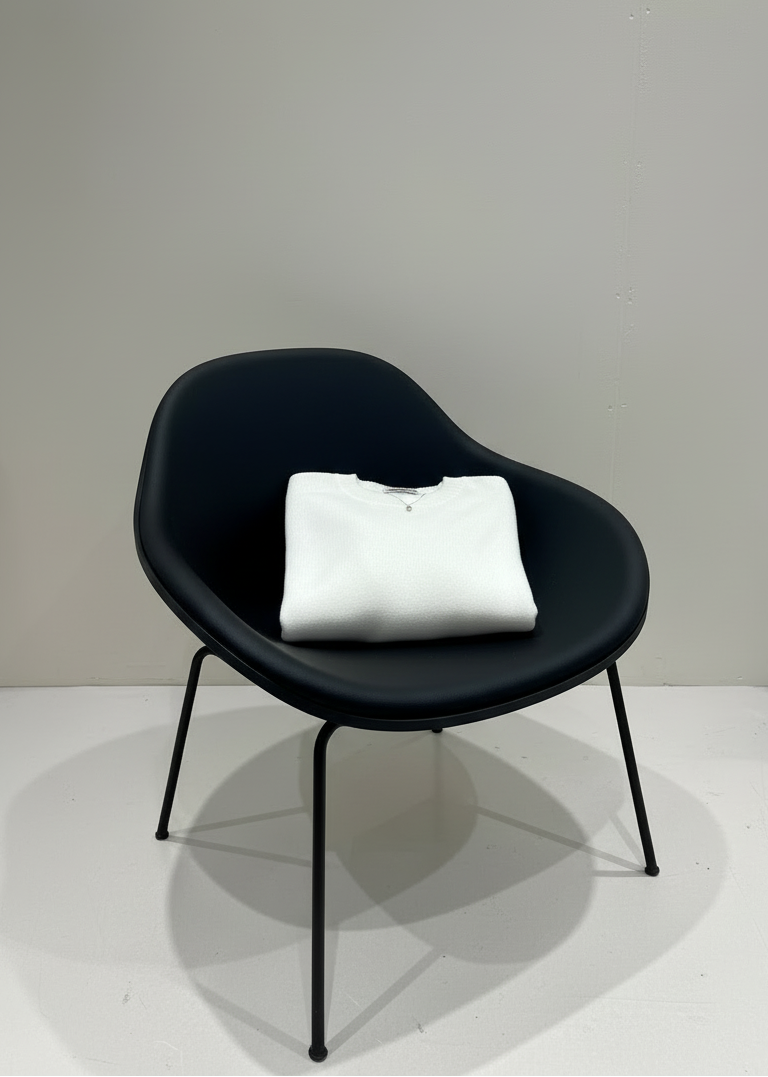 Black chair with a white cushion on a white floor and light gray wall