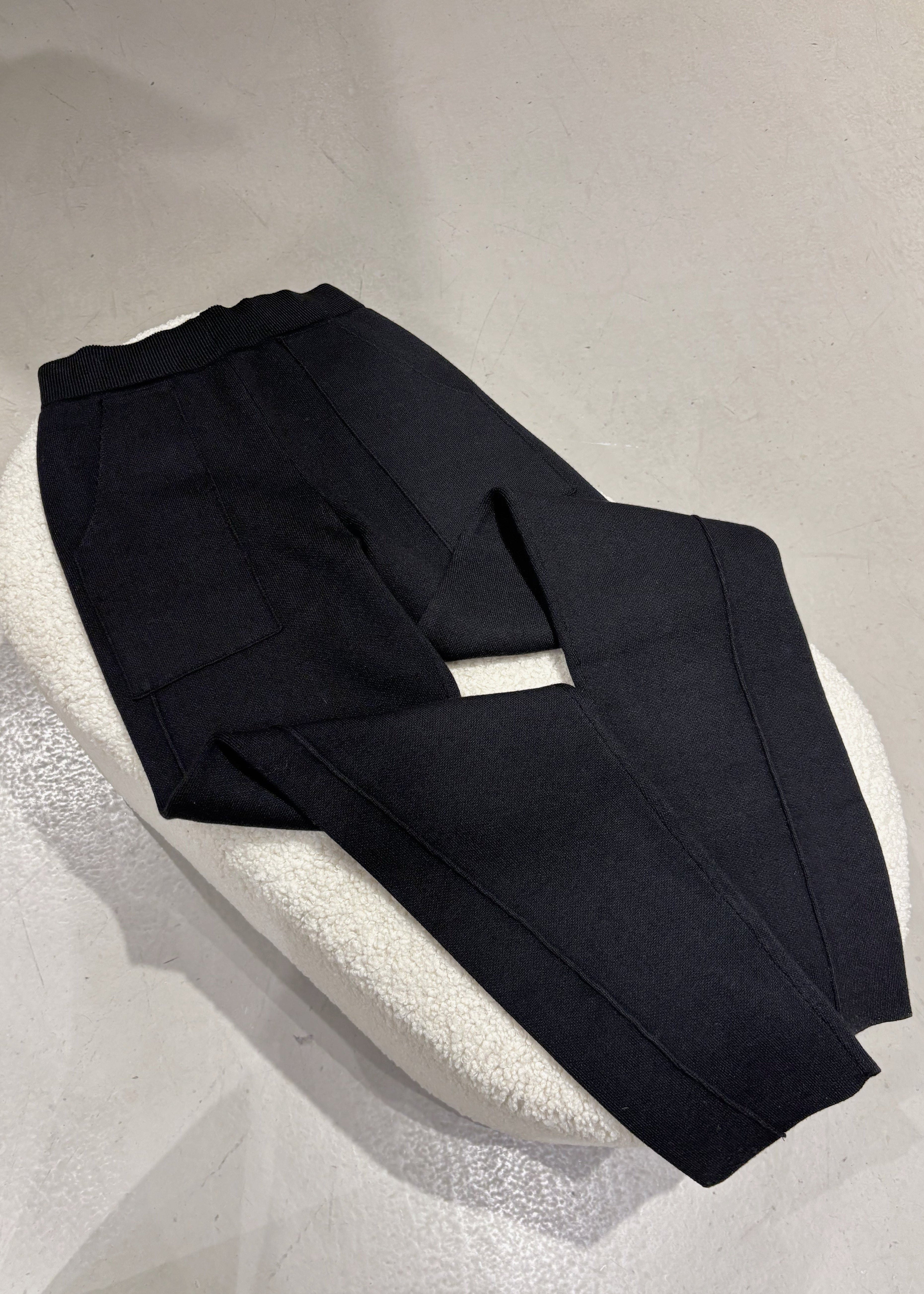 Black pants on a white pedestal against a light gray background