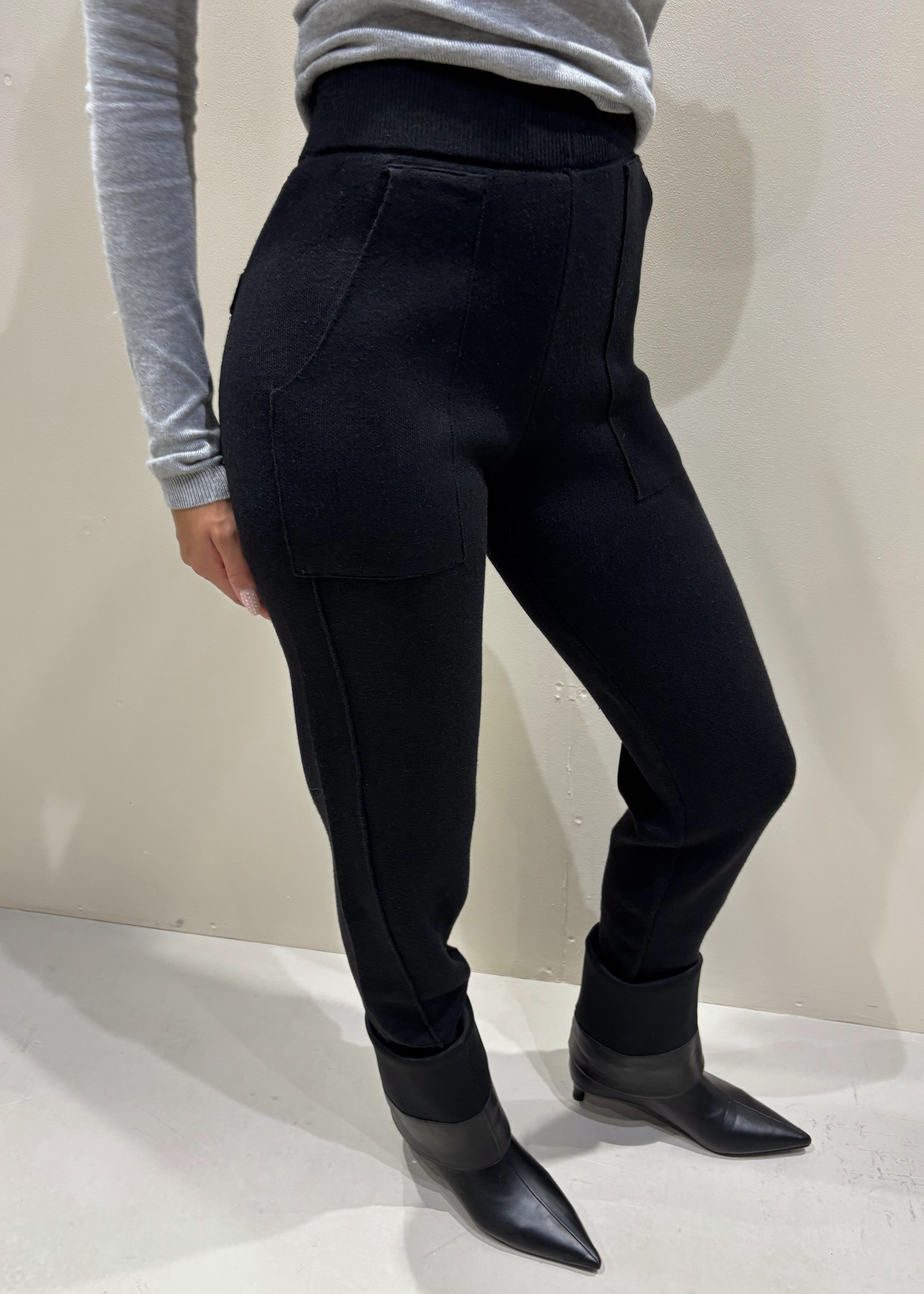 Person wearing black pants and black shoes on a plain background