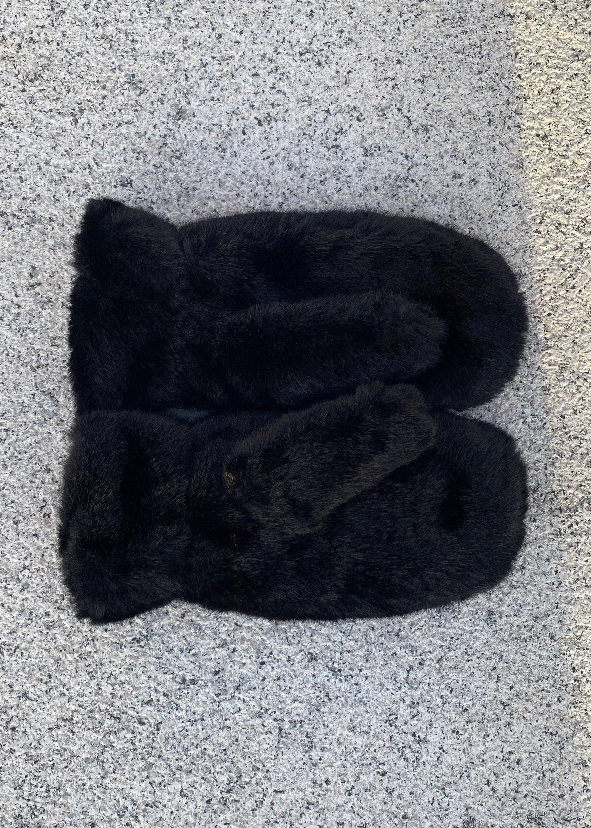 Pair of black mittens on a gray surface
