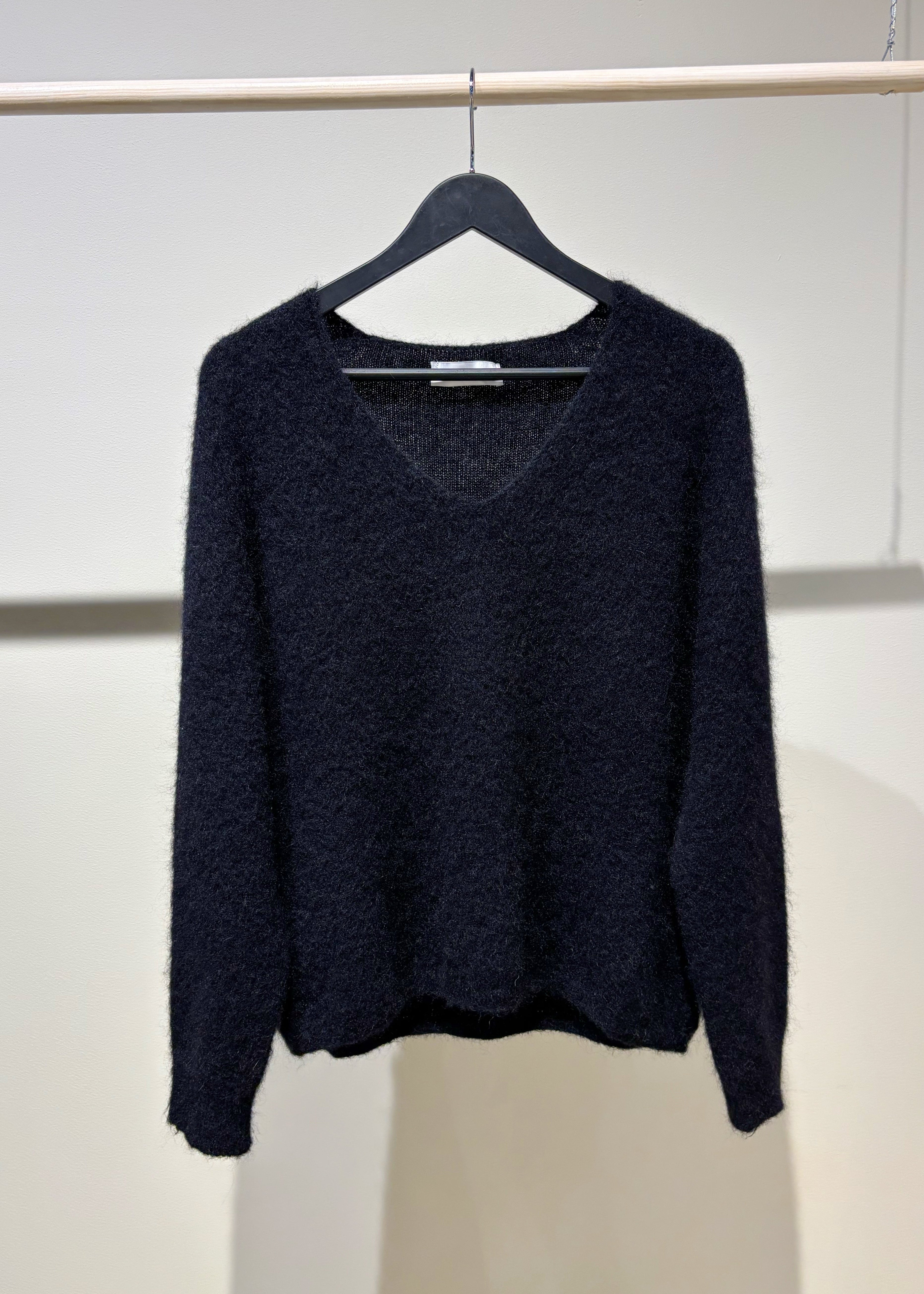 black sweater on a hanger against a white background